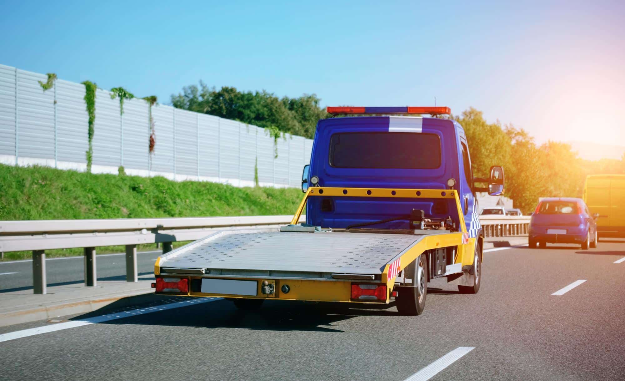 Blauer Abschleppwagen holt ein Auto kostenlos zur Autoentsorgung ab